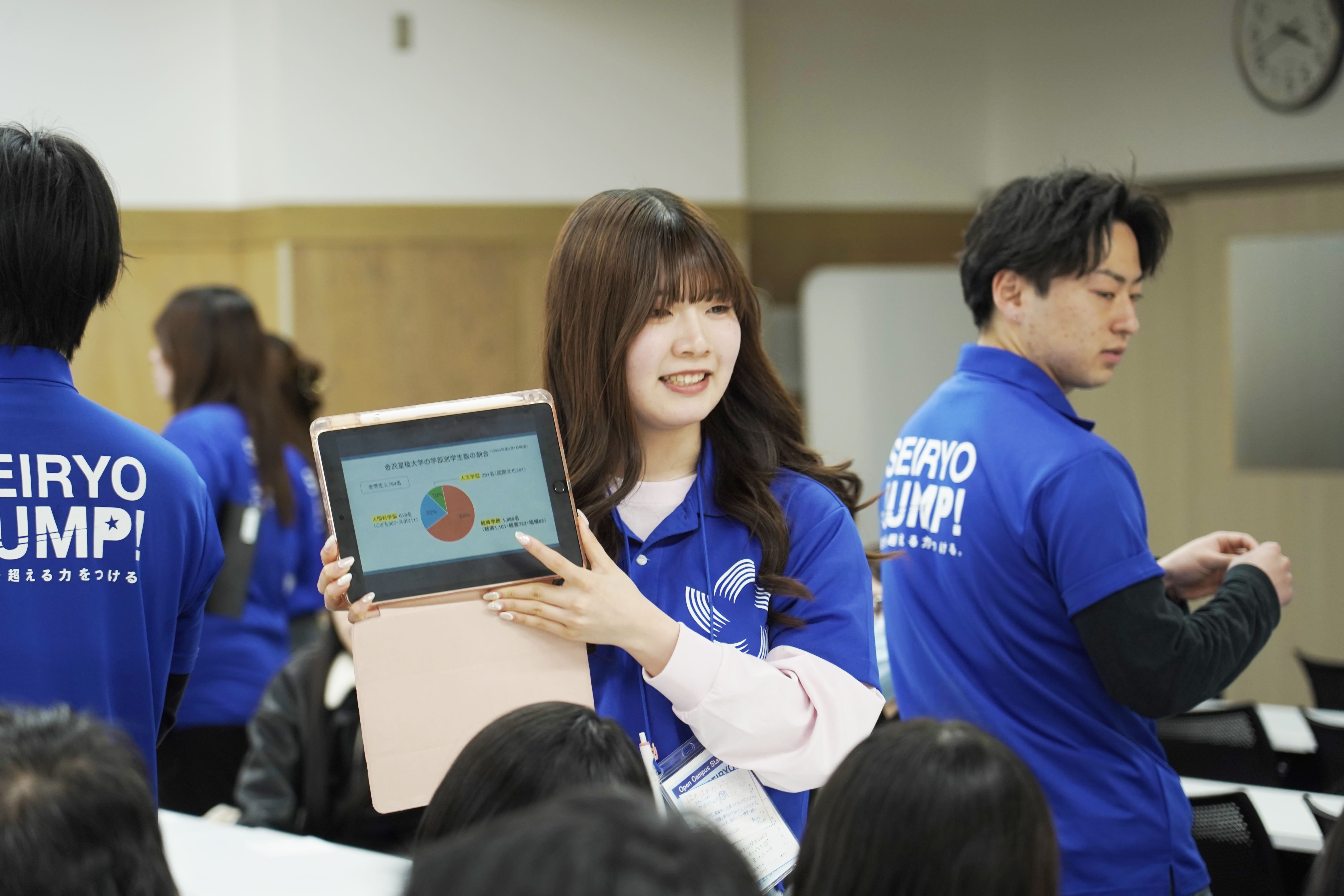 オープンキャンパス説明中にタブレットで説明する学生