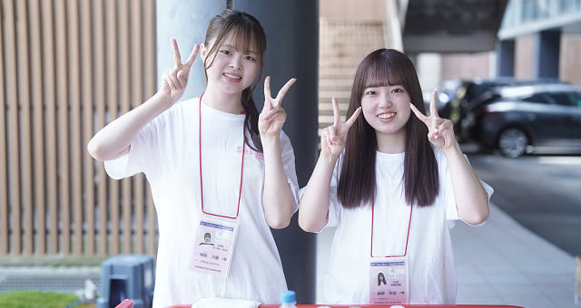 受付でピースする二人の女子学生