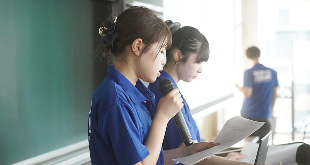 説明文を見ながら説明している学生