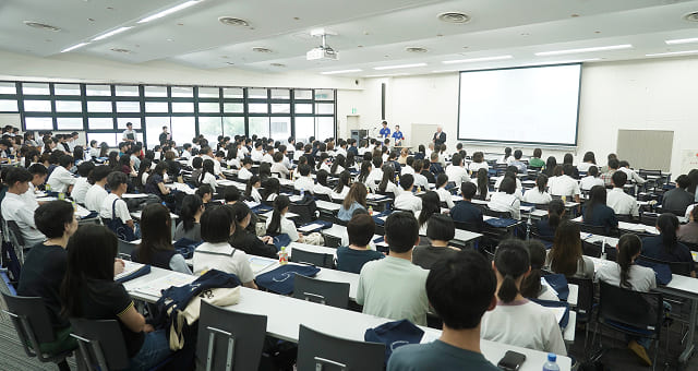広い講義室でたくさんの学生が集まっている様子